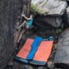 Blaue Ocun Sitcase Bouldermatte unter einem Boulderer zwischen großen Crashpads.