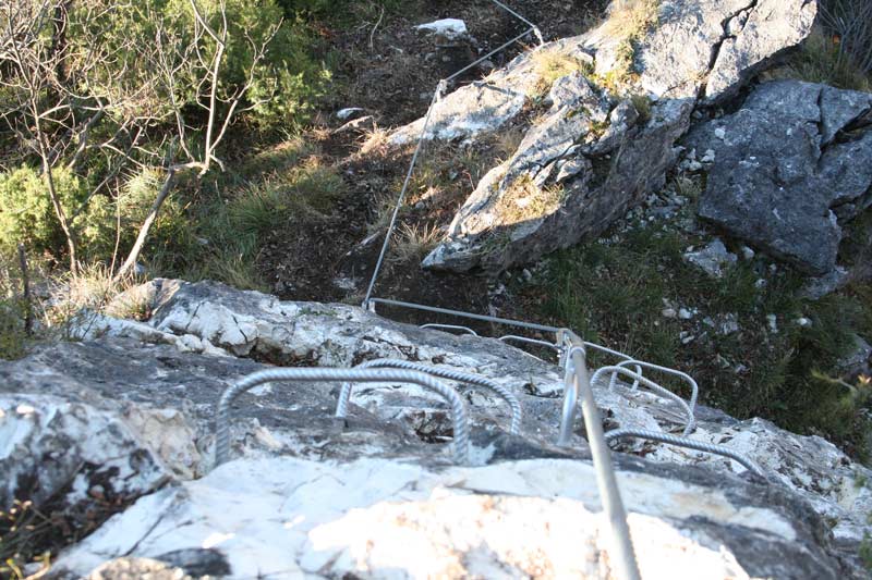 Das Bild zeigt die Klettersteig Errichtung mit massivem Einsatz von Trittbügeln und Griffbügeln an einer grauen Felswand.
