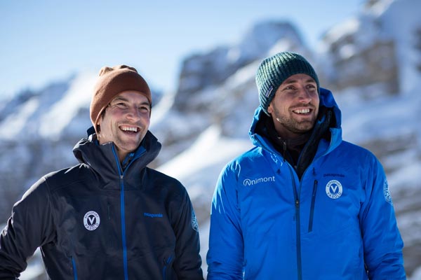 Das Bild zeigt die beiden Bergführer der Alpinschule Animont, Oliver Rohrmoser und Armin Fuchs in blauen Jacken vor einer winterlichen Bergkulisse.