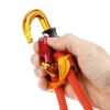 Das Bild zeigt den goldgelben Petzl SMD Twist Lock Karabiner geöffnet in einer Hand und an einem Tibloc mit rotem Seil hängend.