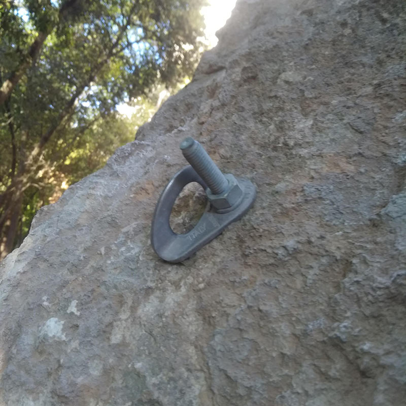 Das Bild zeigt einen Bohrhaken mit Lasche mit viel zu großem Überstand des Gewindes in einer grauen Felswand.