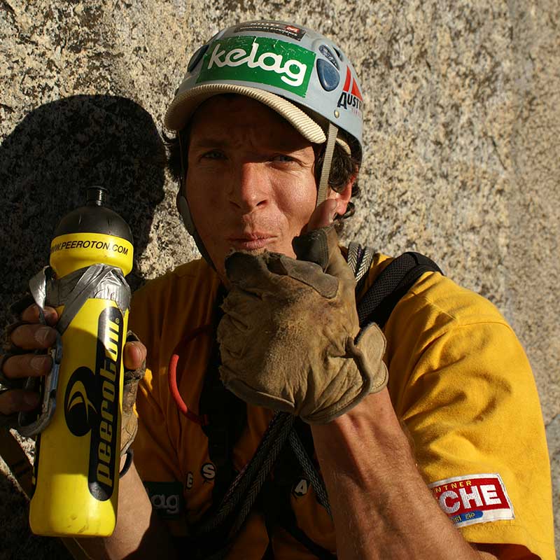 Das Bild zeigt einen Kletterer am Stand mit Helm, Trinkflasche und ledernen Handschuhen. Er zeigt Thumbs up.
