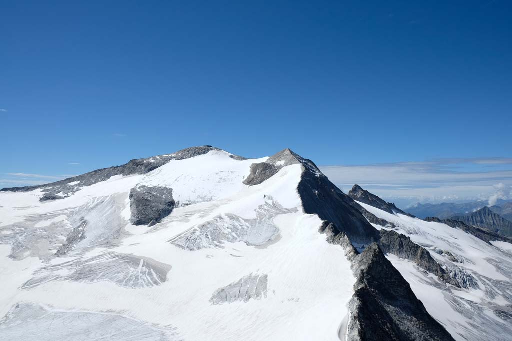 Das Bild zeigt die Nordseite der Hochalmspitze mit dem Hochalmgletscher und Felsen bei blauem Himmel.
