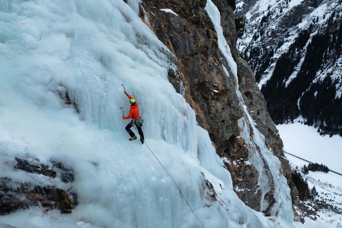 Alpinist mit roter Jacke in leichtem Eisfall zur Demonstration einer leichten Schwierigkeitsbewertungbeim Eisklettern.