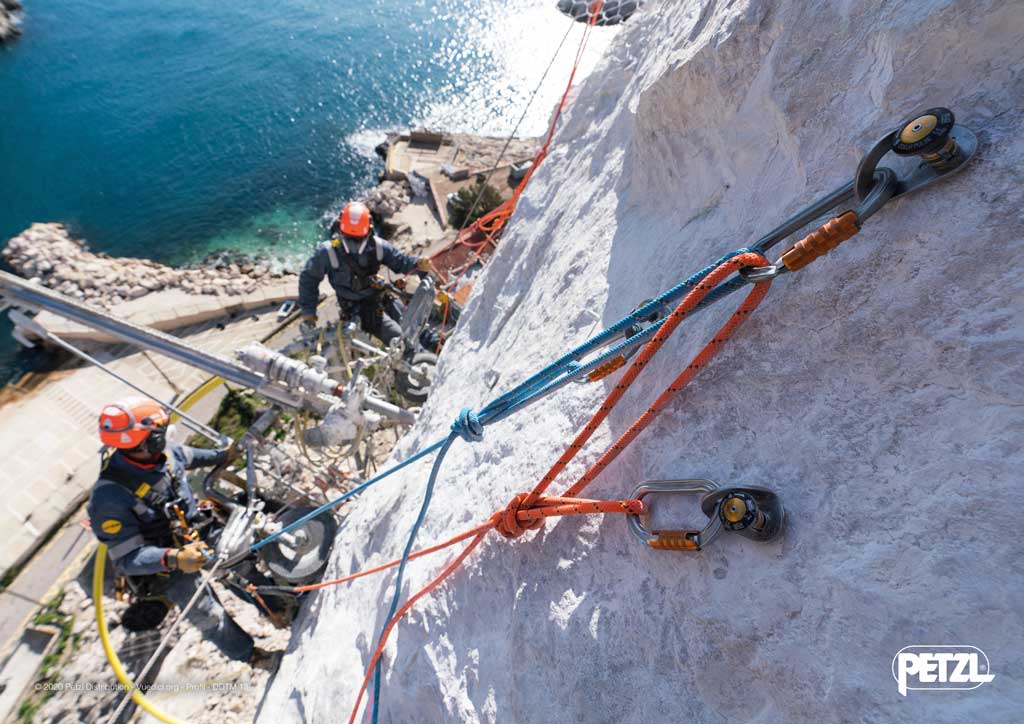 Werbebild des Höhenarbeiter Ausrüstung Shop bolting.eu mit Seilen die an Anschlagmitteln im Fels fixiert sind. Im Hintergrund die Arbeiter und das Meer.