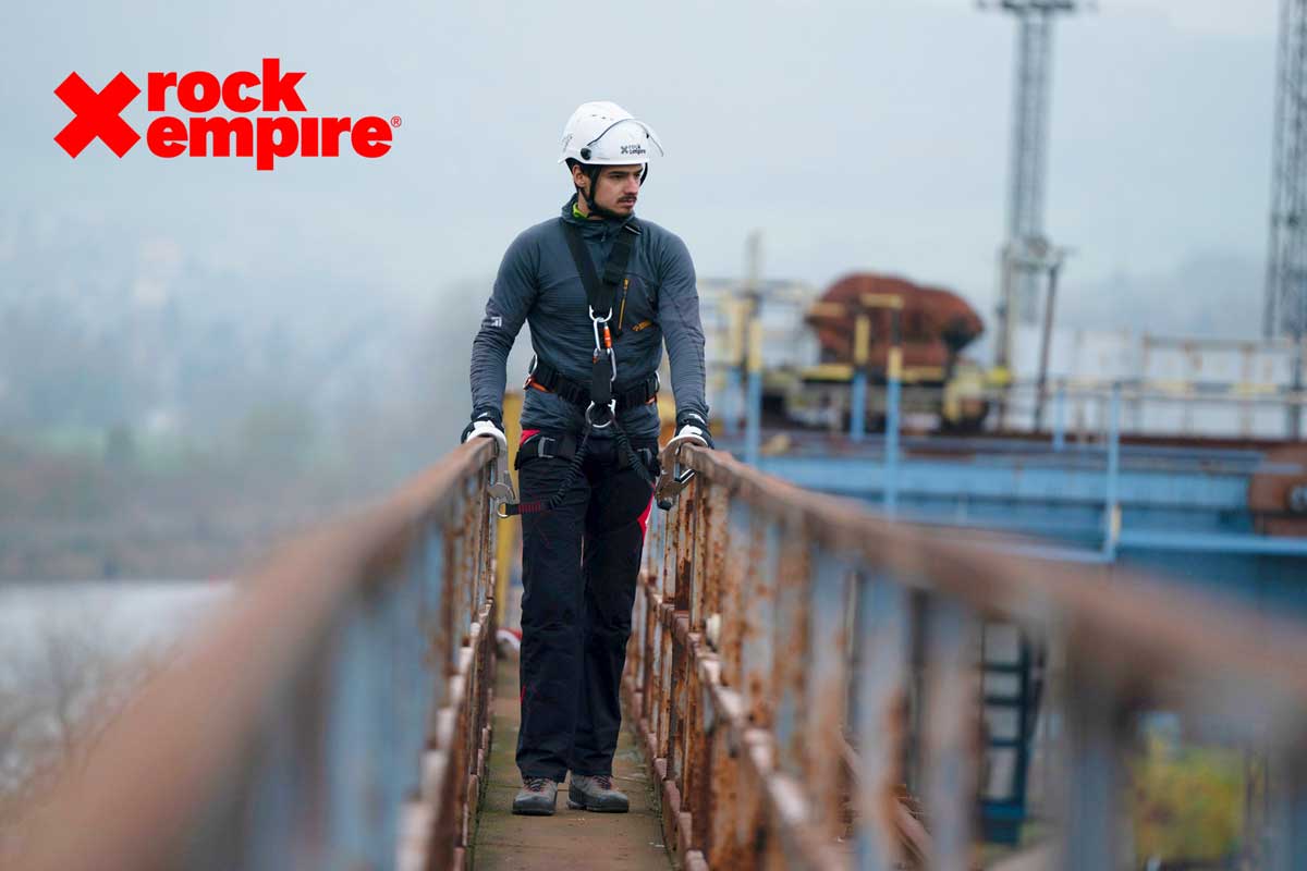 Ein Industriekletterer bei einer Inspektion auf einer Stahlbrücke mit angelegtem Klettergurt und Helm.