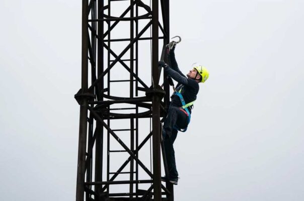 Höhenarbeiter mit Fallgurt und Verbindungsmittel auf einem Stahlturm.