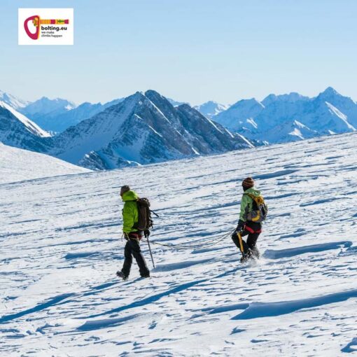 Bergsteiger auf einer Hochtour mit Gipfeln und Himmel im Hintergrund.