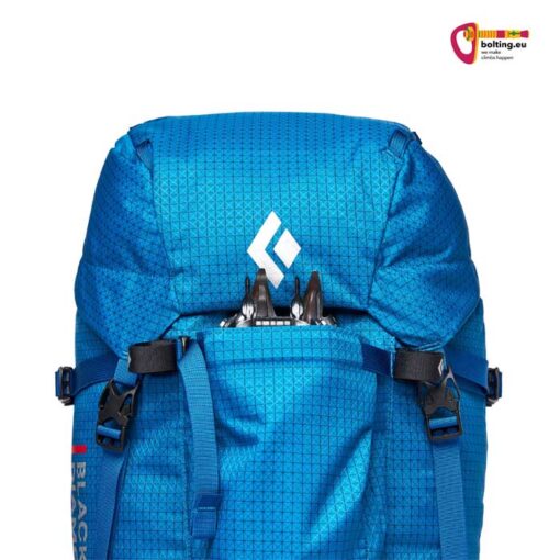 Blauer Alpinrucksack mit Steigeisen in der Steigeisentasche der Vorderseite.