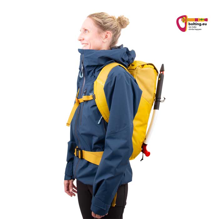Modell in blauer Jacke mit gelbem Kohla Alpinist 22 Hochtourenrucksack und Eisgeräten von der Seite.