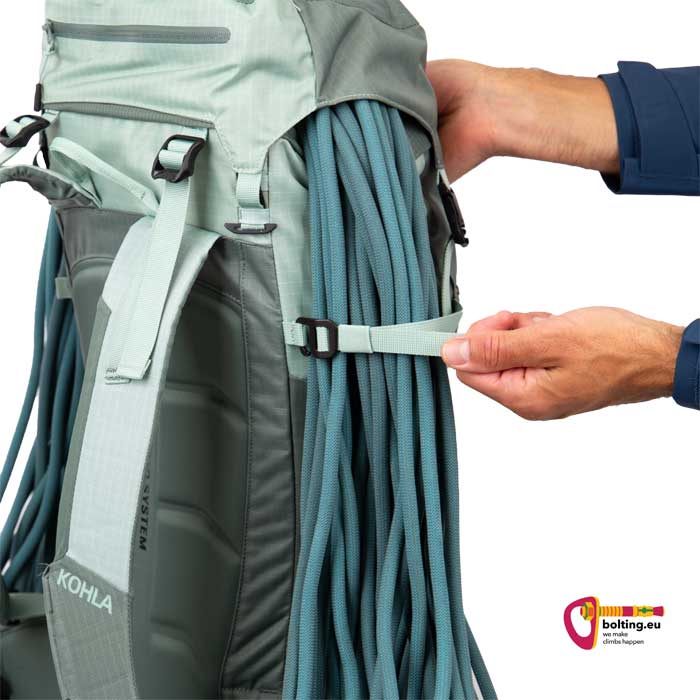 Hand fixiert Kletterseil an lavendelfarbenem Kohla Alpinrucksack.
