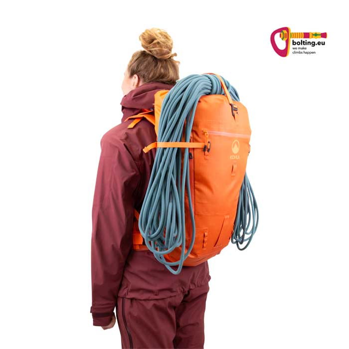 Modell mit lila Überkleidung und orangem Kohla Rucksack.