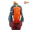 Modell mit orangem Alpinrucksack mit Seil und Eispickeln.