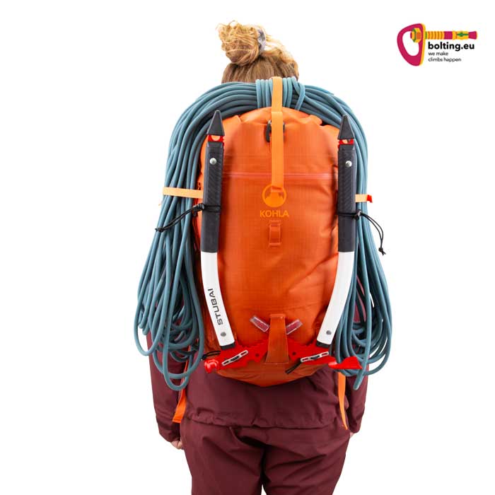 Modell mit orangem Alpinrucksack mit Seil und Eispickeln.
