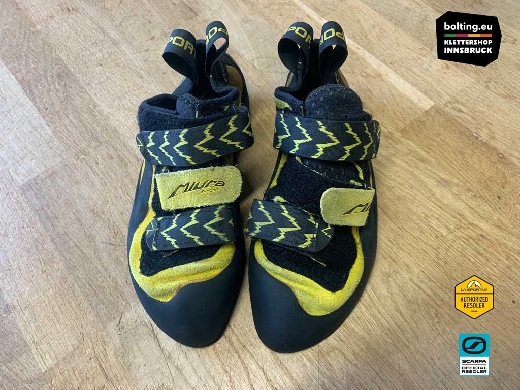 Ein Paar gelbe Kletterschuhe nach der Neubesohlung von oben auf einer Holzplatte.