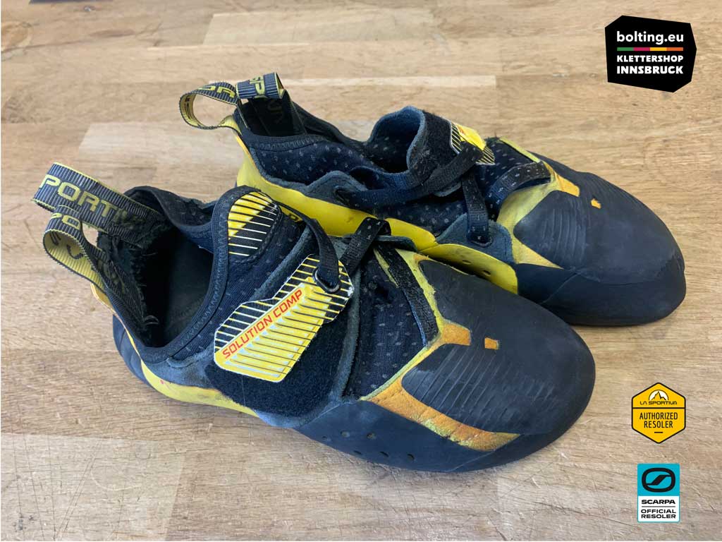 Ein Paar gelbe Kletterschuhe nach der Neubesohlung von oben auf einer Holzplatte.