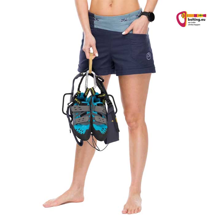 Modell mit blauer Damen Kletter Short und Kletterschuhen vor weißem Hintergrund.