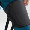 Schwarzer E9 Knieprotektor zum Klettern auf einer blauen Kletterhose.